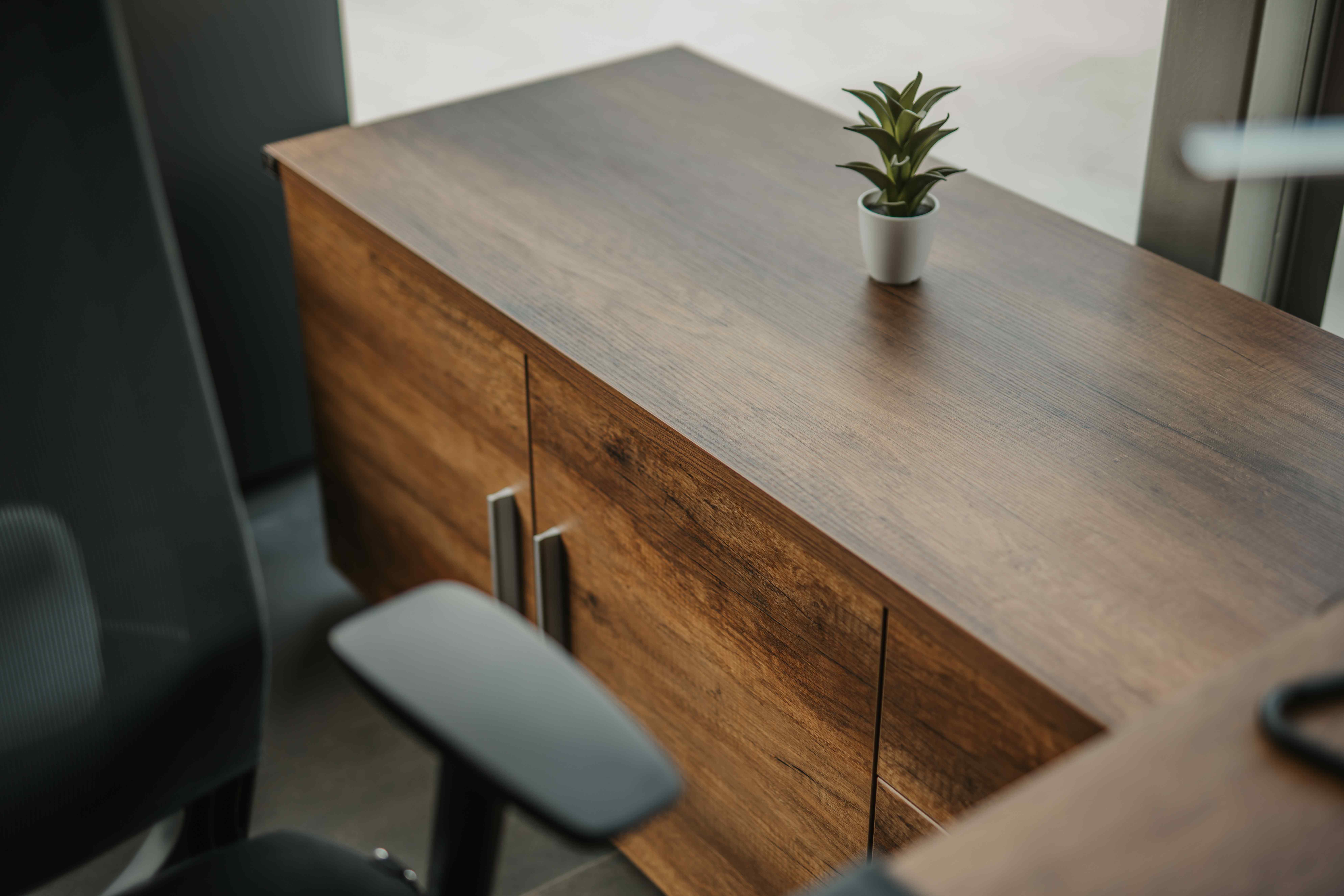 A well-lit desk adorned with a plant, perfectly positioned in front of a window, creating a serene and productive workspace.