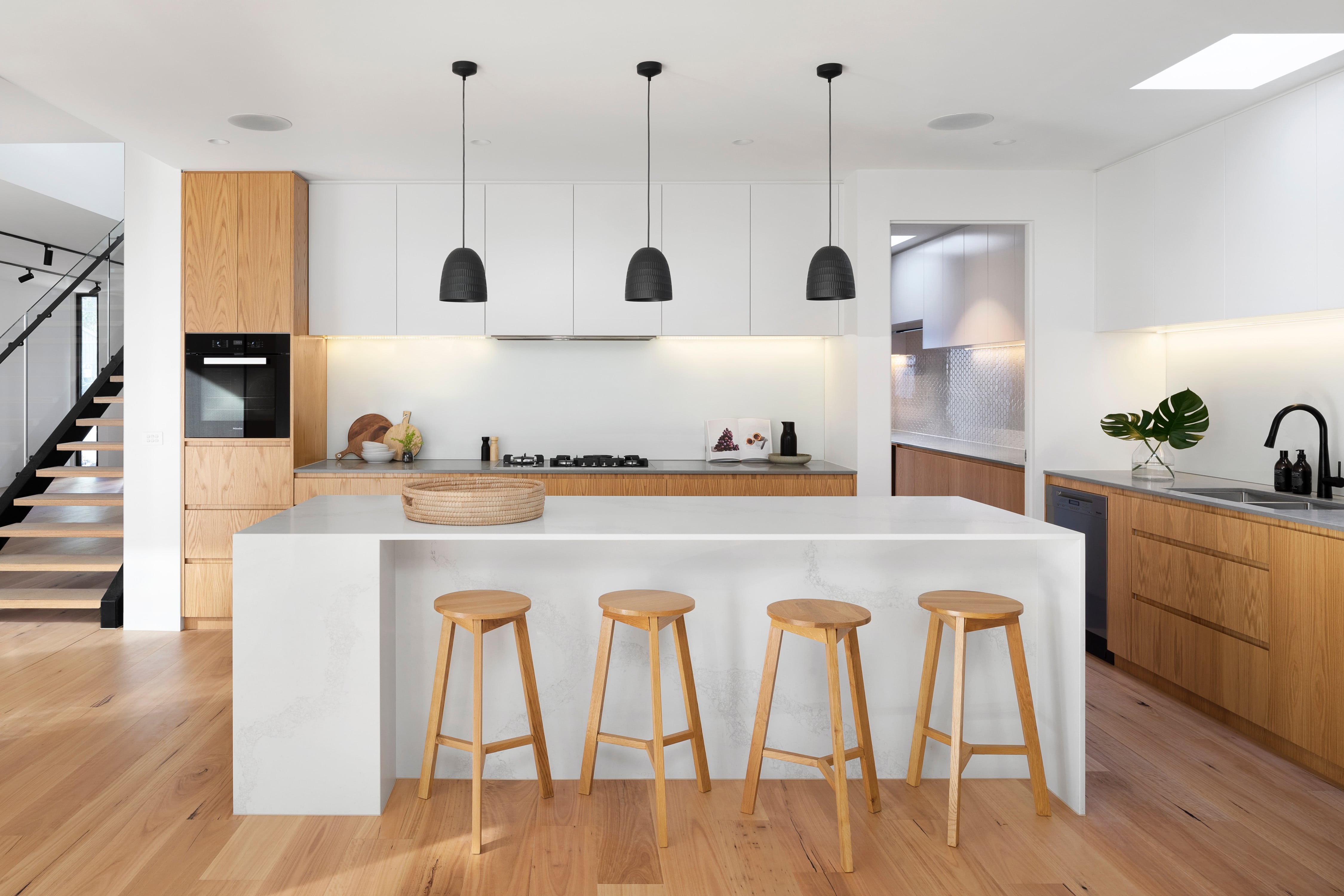 A contemporary kitchen featuring sleek wooden floors and pristine white cabinets