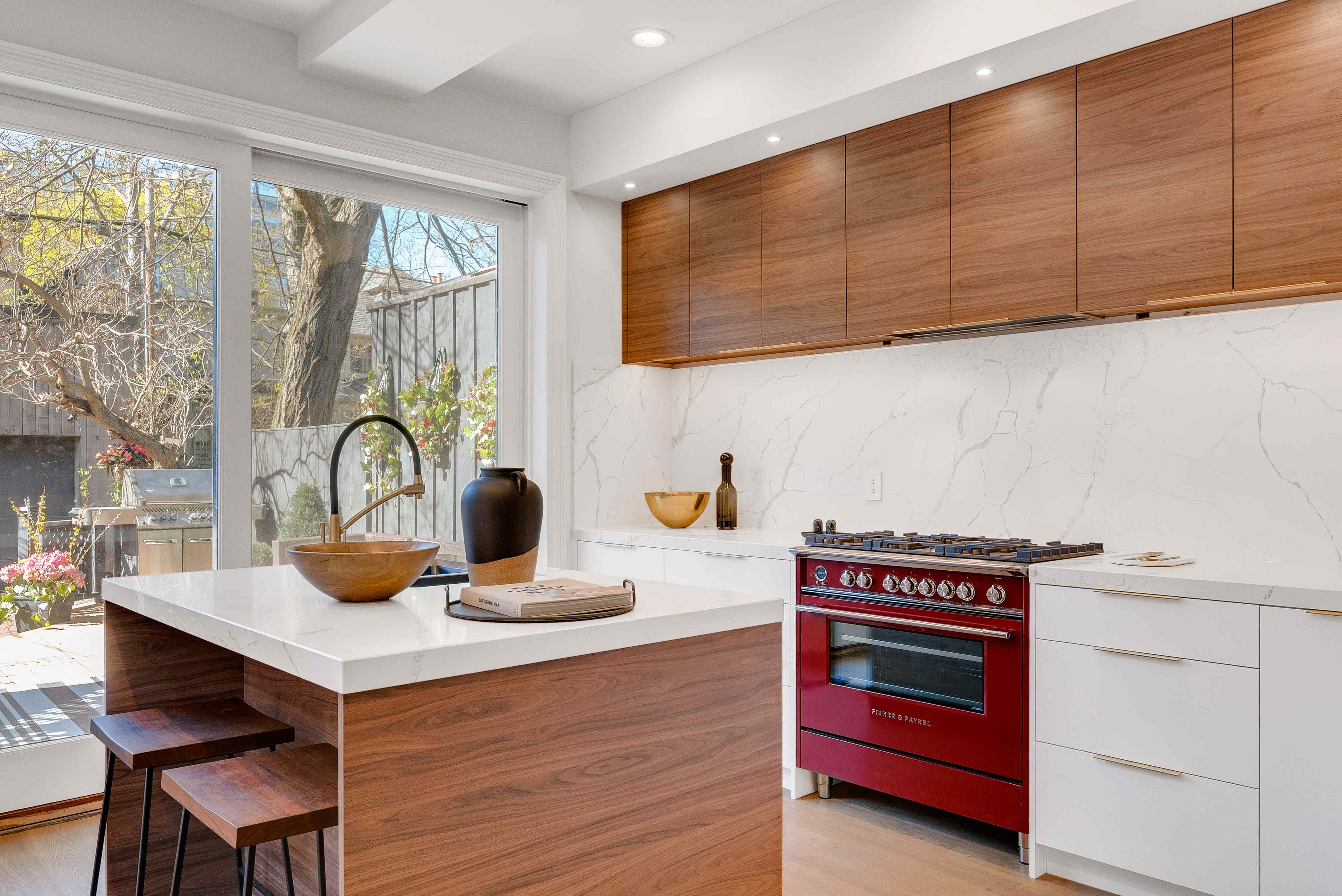 A stylish kitchen showcasing a bold red stove and sleek wooden cabinets
