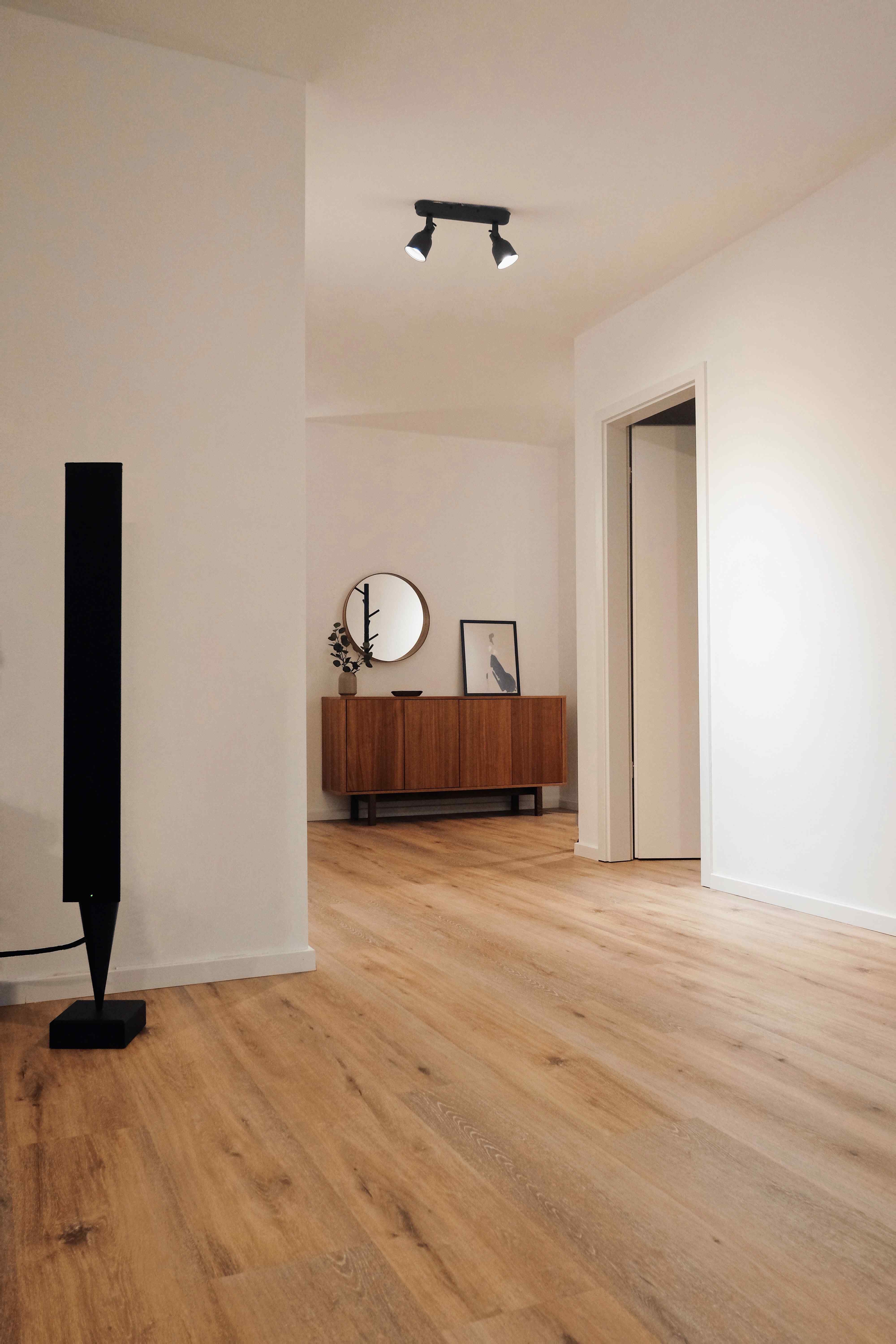 An inviting space featuring wooden floors and a pristine white wall, exuding a sense of warmth and simplicity.